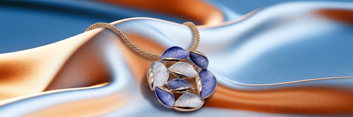 Goldfarbene Halskette mit blau-weissem Blätter-Anhänger auf blau-orangem Stoff
